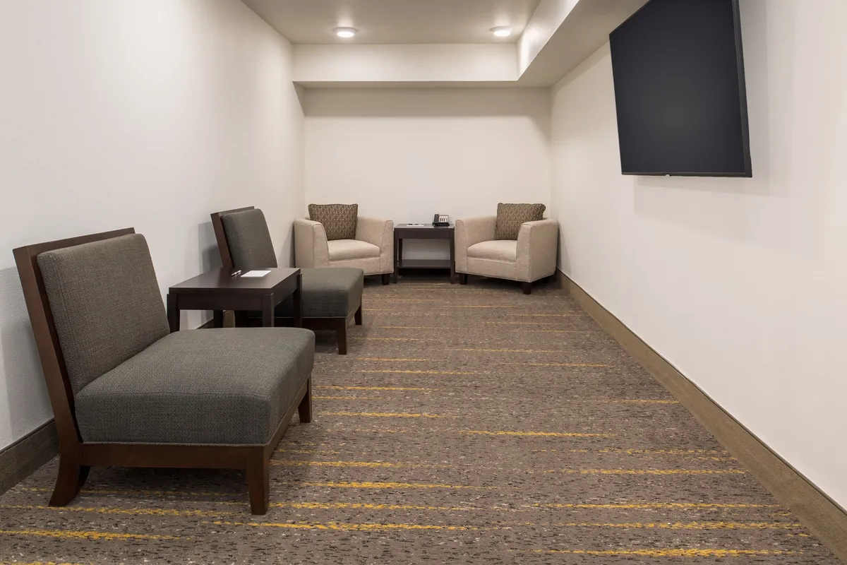 A comfortable and casual living space with a seating area facing a television. The arrangement encourages casual conversations, relaxing, or watching TV, enhanced by the presence of a coffee table and soft lighting. The overall mood is one of relaxation and ease, underscoring the suite's appeal as a personal retreat.
